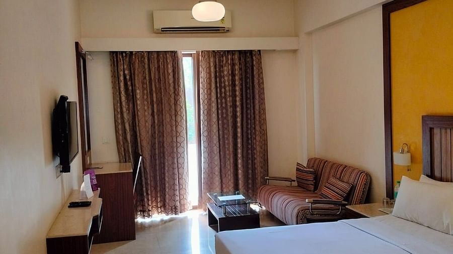 An image of a bedroom featuring a double size bed, a flat TV screen, a dressing table, a  sofa and a centre table - VITS Lonavla