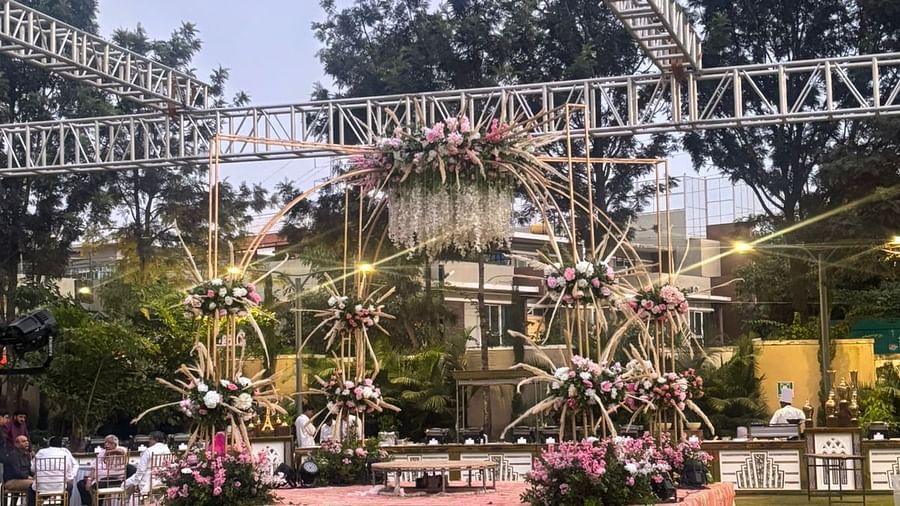 Outdoor stage area decorated with flowers, surrounded by event seating, under a lighting rig during the evening.