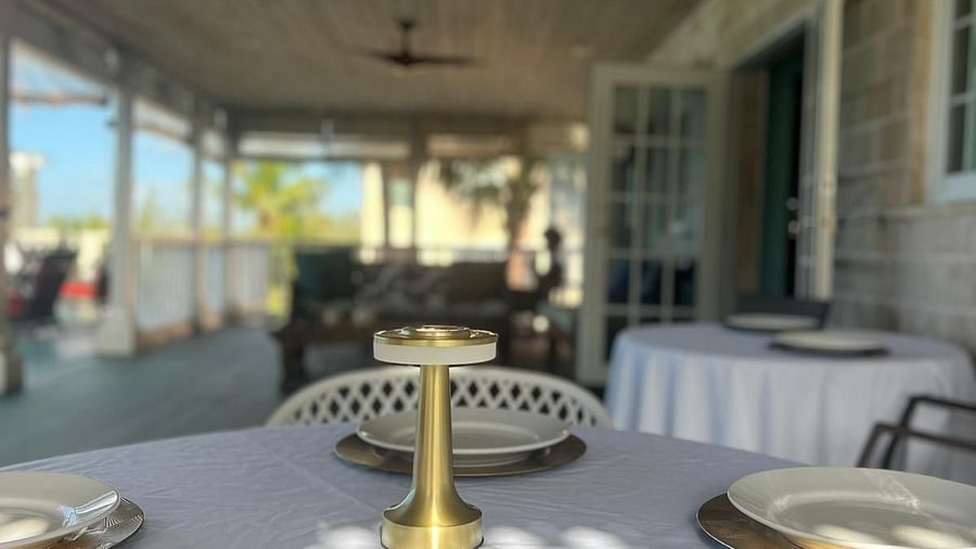 Round table with plates under a ceiling fan on a covered deck | A Stone's Throw Away