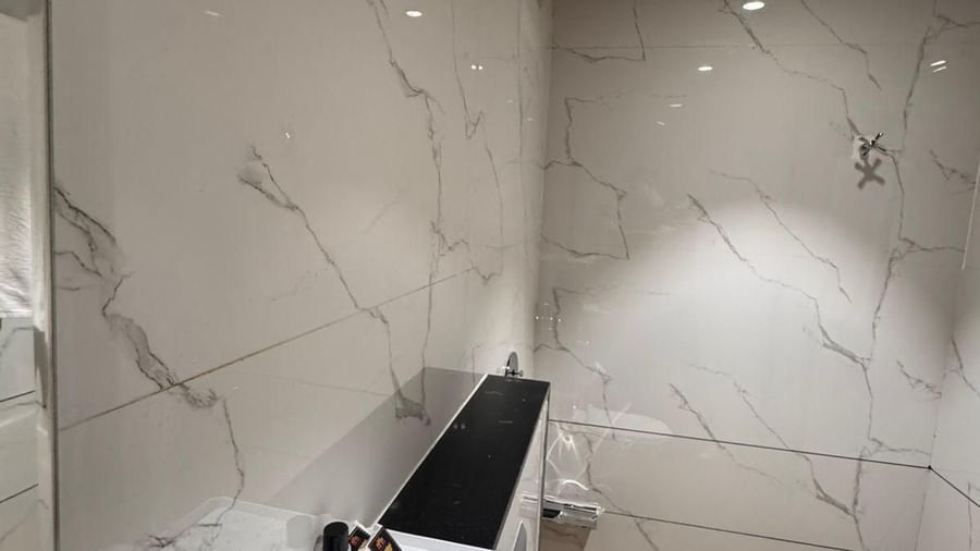 Elegant bathroom with marble walls and modern amenities at Hotel Mumbai House, Vijay Nagar, Indore, designed for comfort and a refreshing stay.