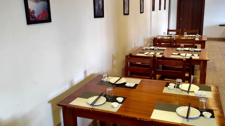 Side view of the Ajito restaurant featuring wooden dining tables with cutlery arranged over it at Ilara Hotels & Spa, Tada.