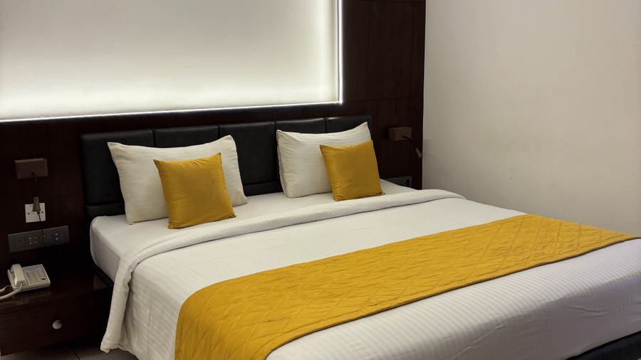A double bed with yellow-coloured bed runner spread over it at the Premier Suite at SRS Suites, Koramangala.