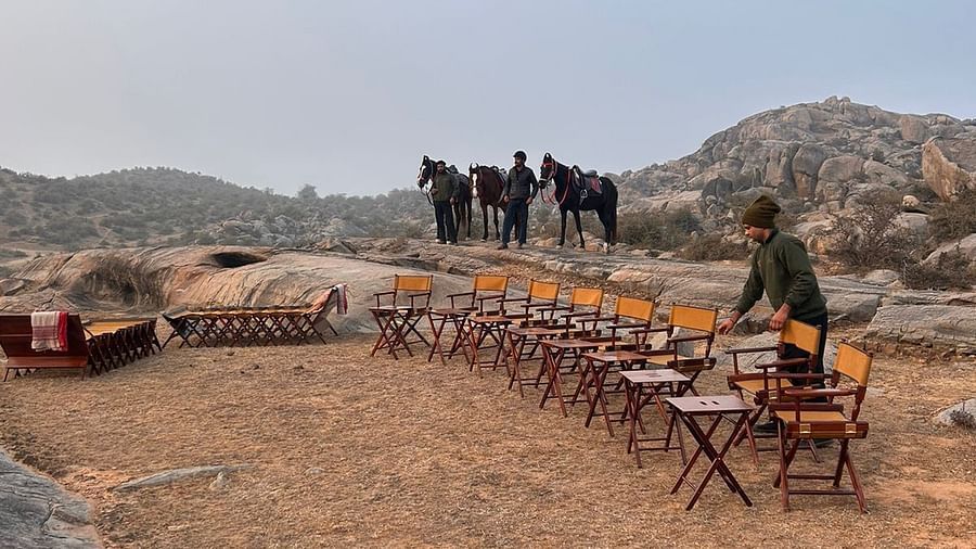 An image of horses near a seating arrangement on top of a mountain with view of the mountains - Utsav Camp Sariska
