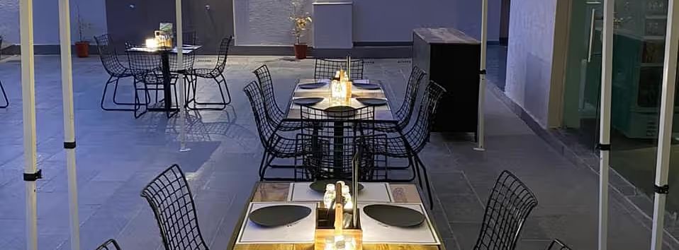 Long dining table with place settings, tented ceiling, evening.