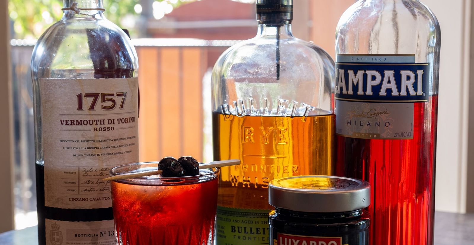 Assortment of spirits and ingredients for classic cocktails displayed by a window at The Groveland Hotel.
