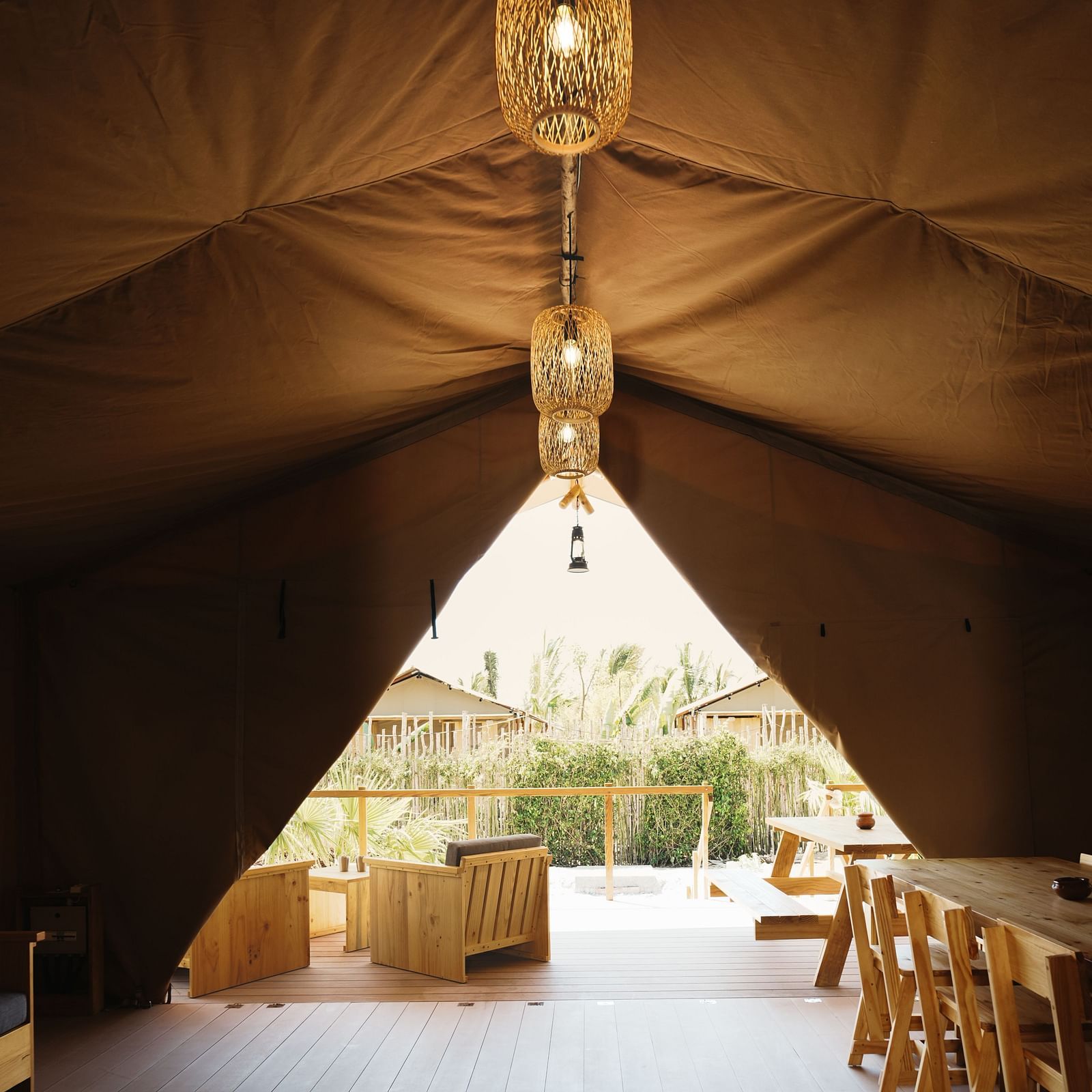 A glamping tent at WoCAL Retreat Ke Ga features a warmly lit interior with wooden furnishings and inviting seating.