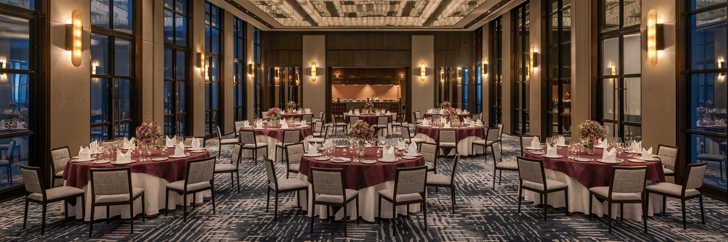 Gallery function room set up for a gala dinner with round tables at twilight at The Residency Signature Madurai.