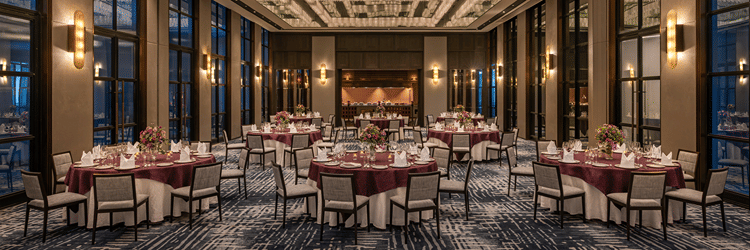 Gallery function room set up for a gala dinner with round tables at twilight at The Residency Signature Madurai.