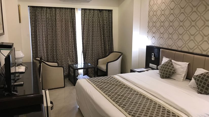 Room at Kohinoor Executive - Deccan Gymkhana, Pune with a large neatly made bed, patterned wallpaper, seating area by the window, and soft ambient lighting