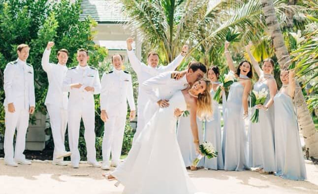 Group of people in dresses and suits posing for a wedding photo among palm trees, Abaco Inn.