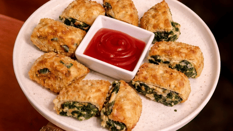A plate containing sliced rolls and a small bowl of red dipping sauce is displayed at Amantra Shilpi Resort, Udaipur.