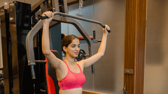 Woman performing an exercise on a seated pull-down machine in a modern resort gym.