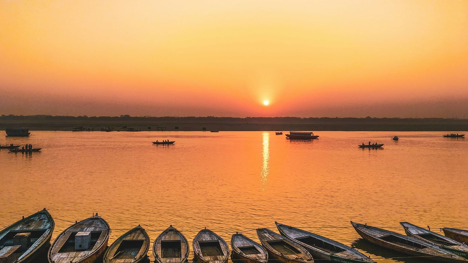 view of the lakes at sunset with boats placed on the shore 