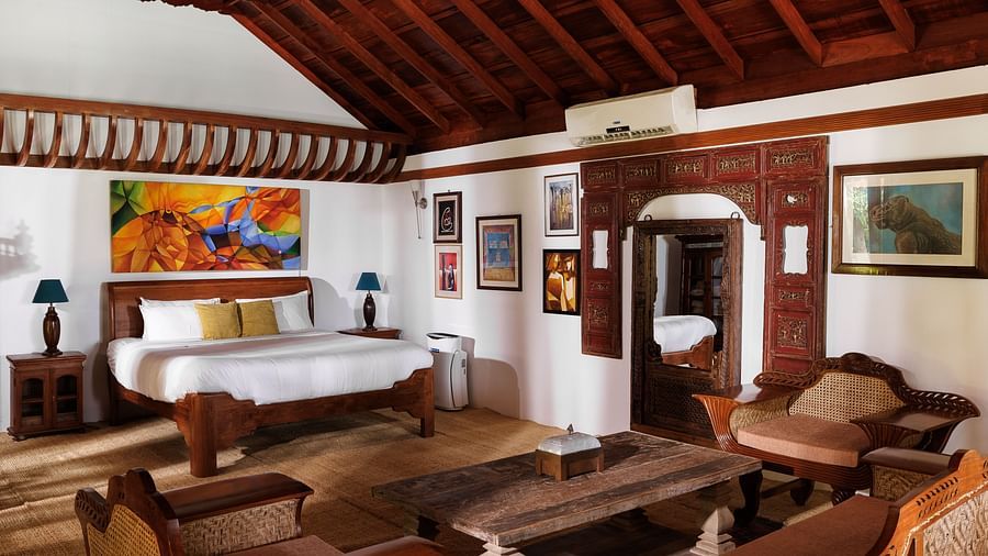 A wooden interior room with wooden furnitures such as a bed, a sofa set, a coffee table, and paintings - BluSalzz Villas - Muhamma Resort, Alleppey