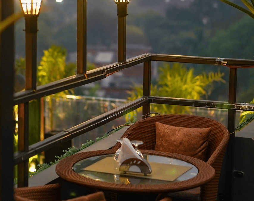 2 chairs facing each other on a terrace with warm lights beside it on a late evening.