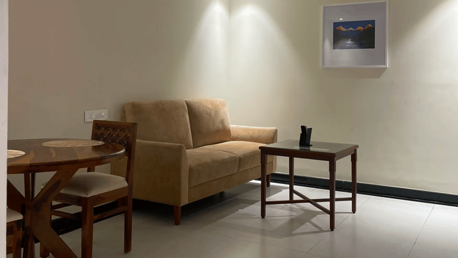 A seating area with a sofa, a table, chairs, and a wall mounted frame. | MM Legacy, Kanchipuram