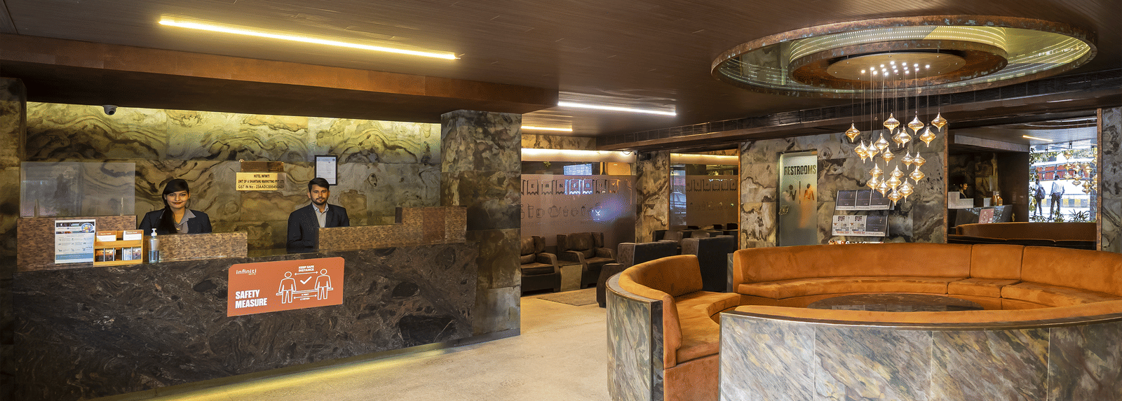Spacious lobby with marble flooring, a rounded front desk, and ambient ceiling lighting at Infiniti Hotel, Indore.