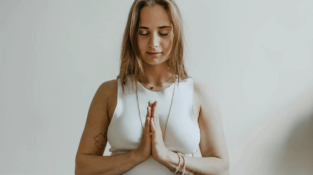 A woman doing meditation sitting on a yoga mat.