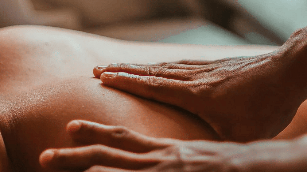 A massage therapist massaging the back of  a person in the spa.