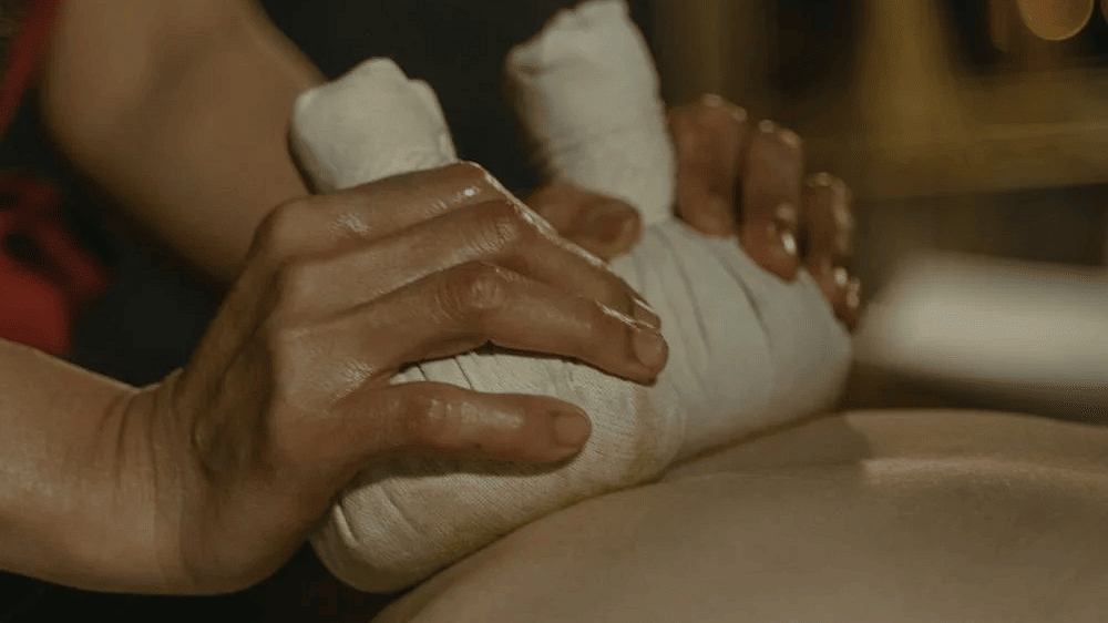 A massage therapist massaging the back of a person in a spa.