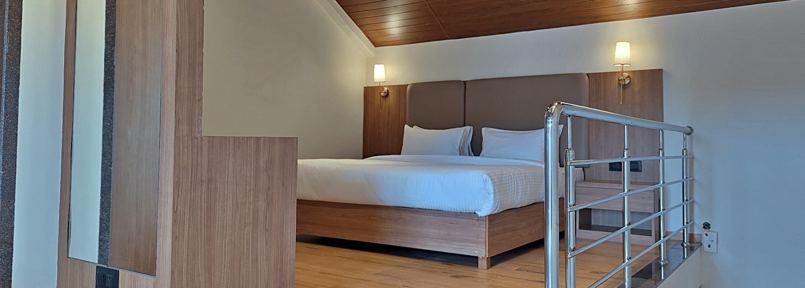 Bedroom with a double bed, wooden furnishings, loft area, and railing.