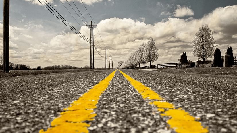 A close up shot of a highway with yellow lines in the centre and power lines on the side - Black Thunder Ooty Main Road Mettupalayam.