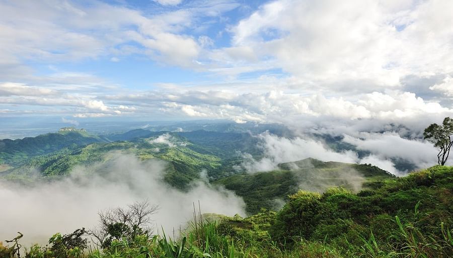 A view of a mountain range covered in mist, with a clear blue sky in the background.