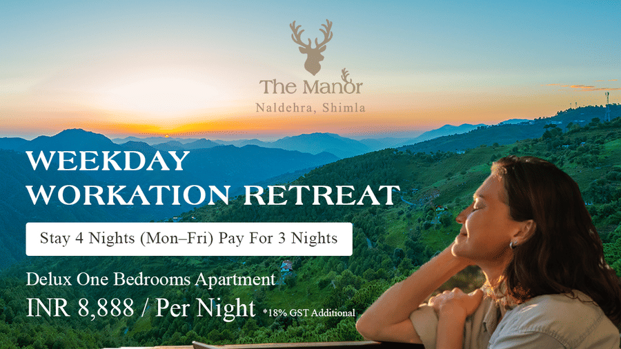 Woman sitting on balcony with laptop overlooking green hills and sunset at The Manor Naldehra, Shimla. Promotion for weekday workation retreat offering stay 4 nights pay for 3 nights in Deluxe One Bedroom Apartment at INR 8,888 per night, including high-sp