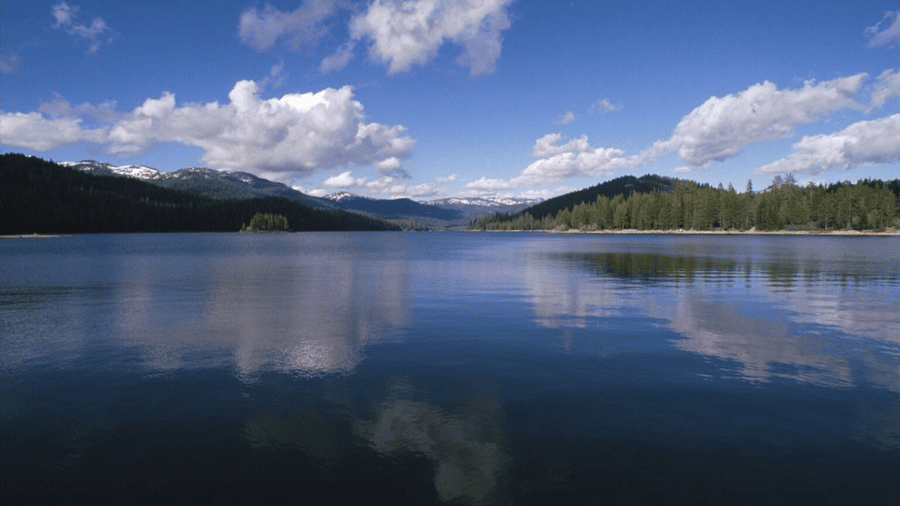 The view of the lake with the reflection of the hills and the clouded sky.