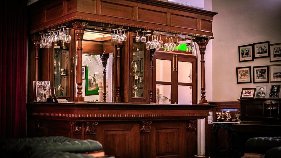 A classic, ornate wooden bar with hanging glassware and framed pictures on the wall - Khas Bagh, Jaipur