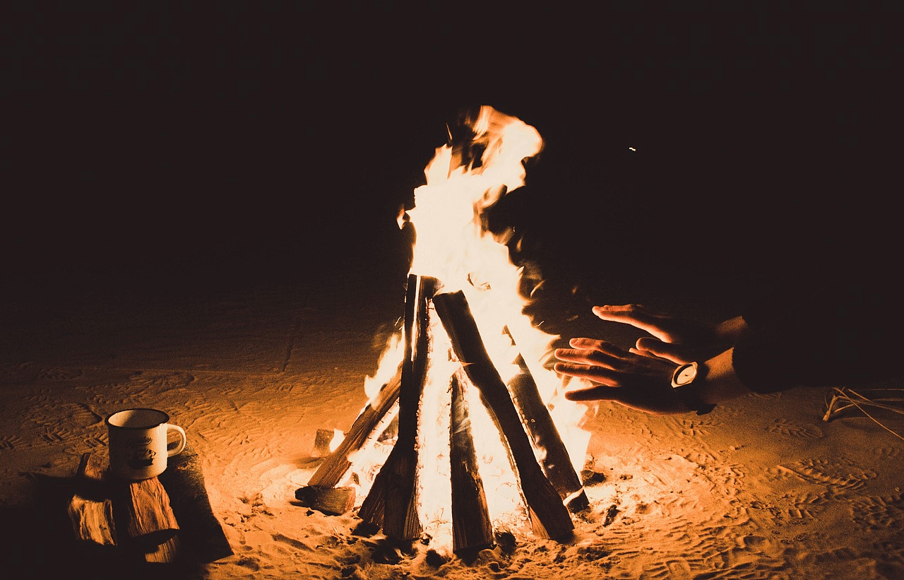 An image of a bonfire and people surrounding it