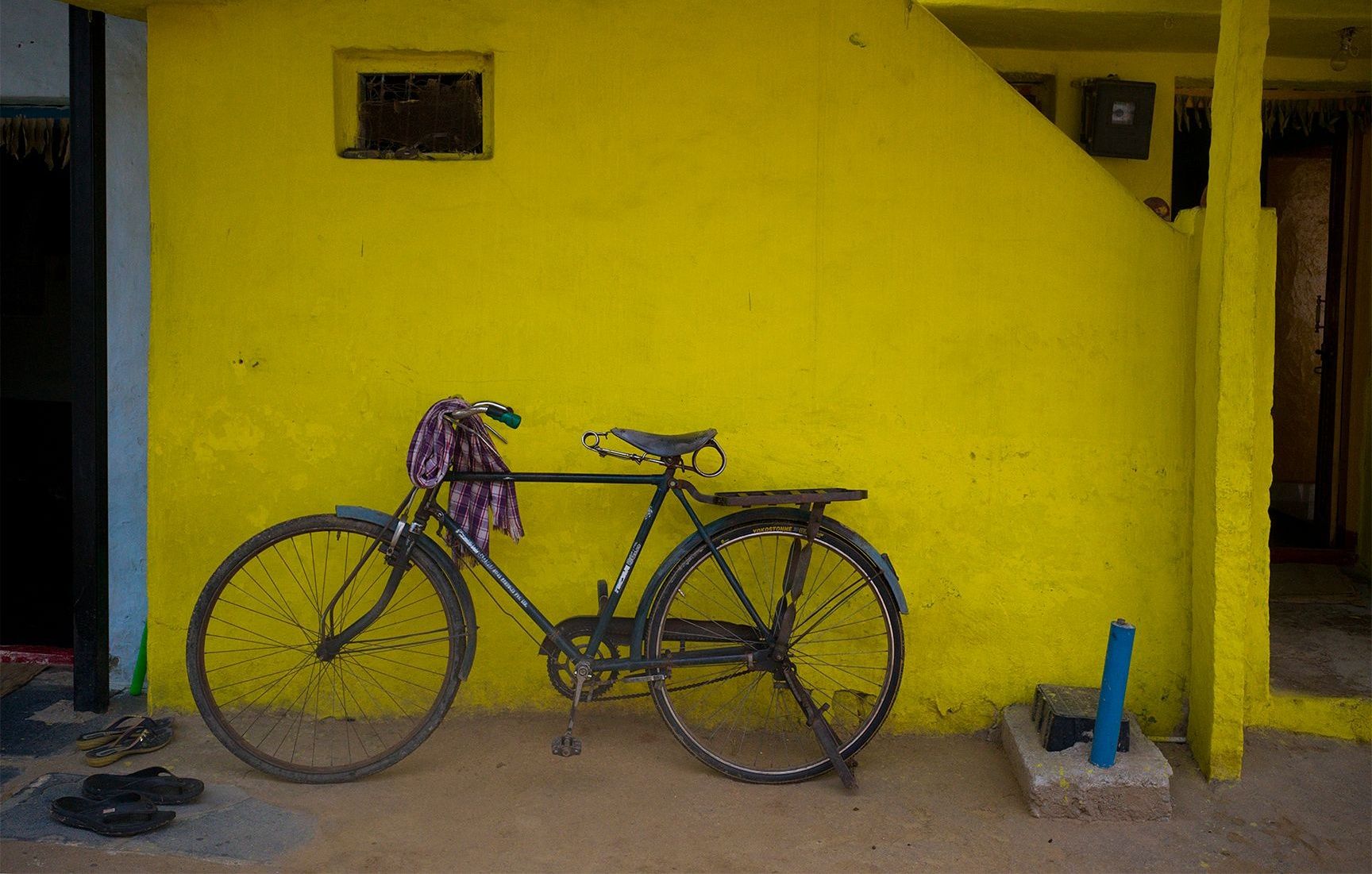 Old bicycle against a vibrant yellow wall in Hampi.