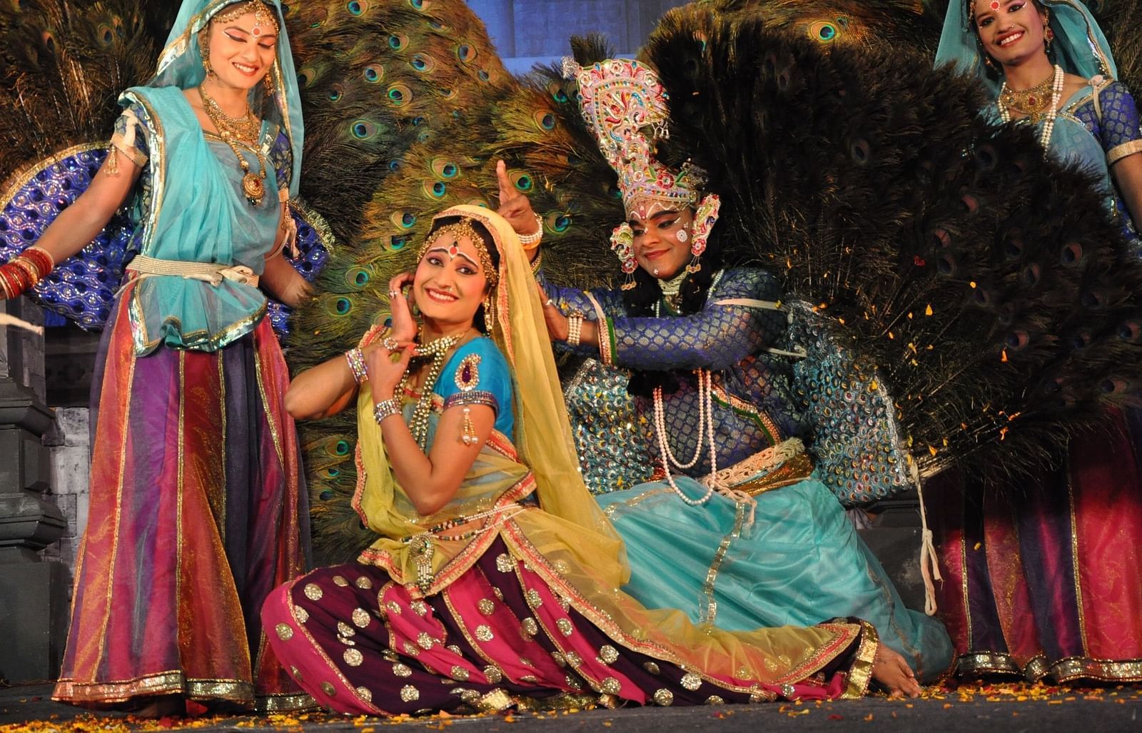 An image of drama stage with three people in traditional attire performing an act 