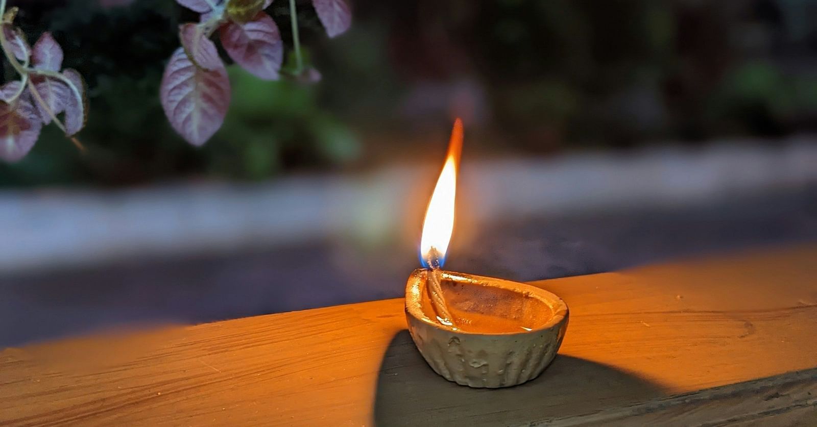 A flickering flame within a small, traditional oil lamp, casting a warm glow in a serene, dim setting.