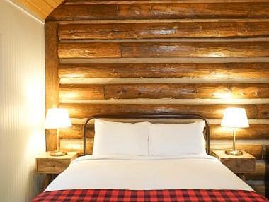 A room with a double bed and side tables with night lamps placed on it - Shaver Lake Village Hotel.