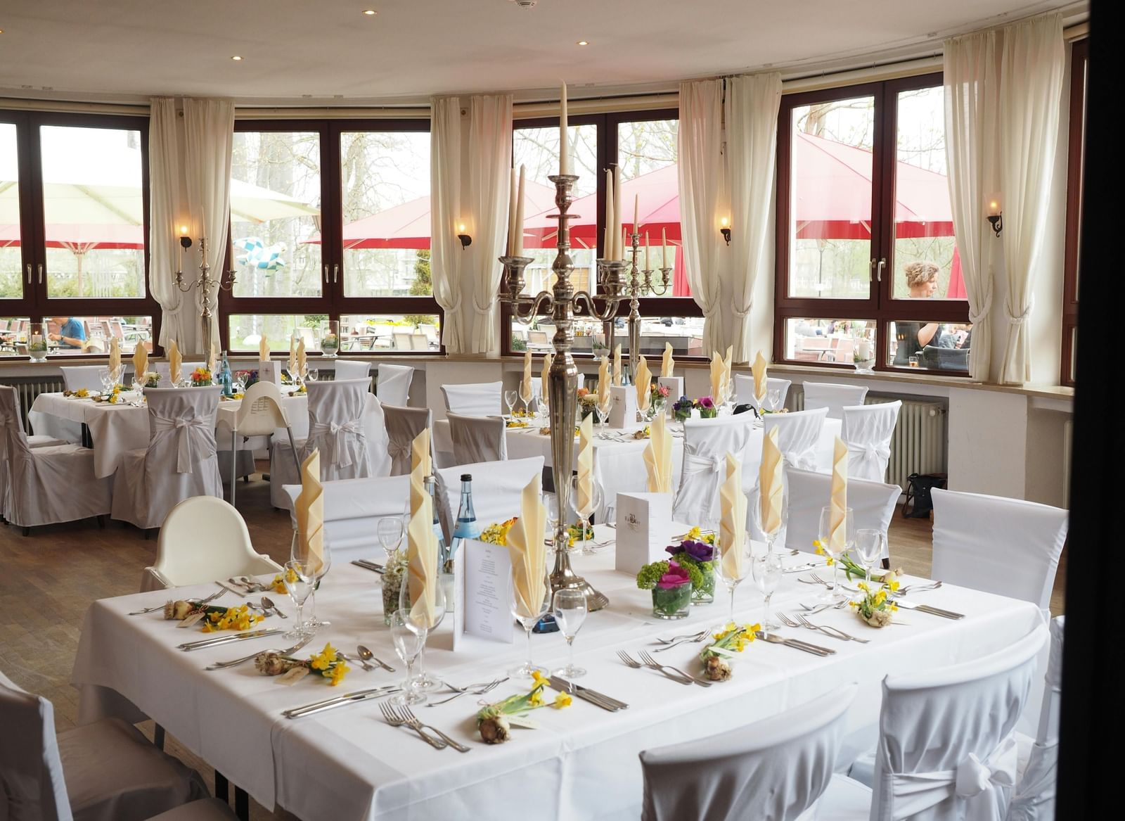 A large event space or banquet hall set up with multiple round tables covered in white tablecloths and decorated for a formal occasion.