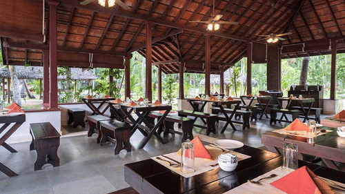 Open hall restaurant in Abad Turtle Beach Resort, the best resort in Alleppey, featuring dining tables and benches prepared to serve guests