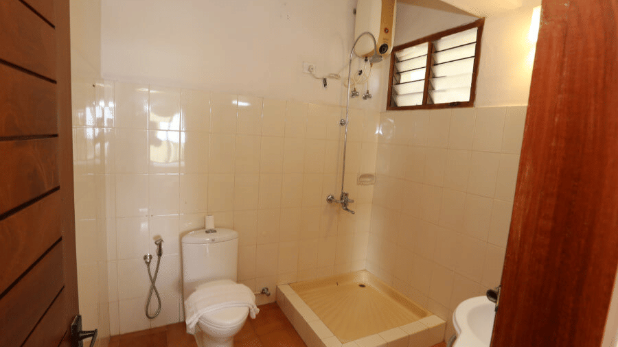 A bathroom in a superior room at Abad Serviced Villas, Kovalam with a toilet area and window