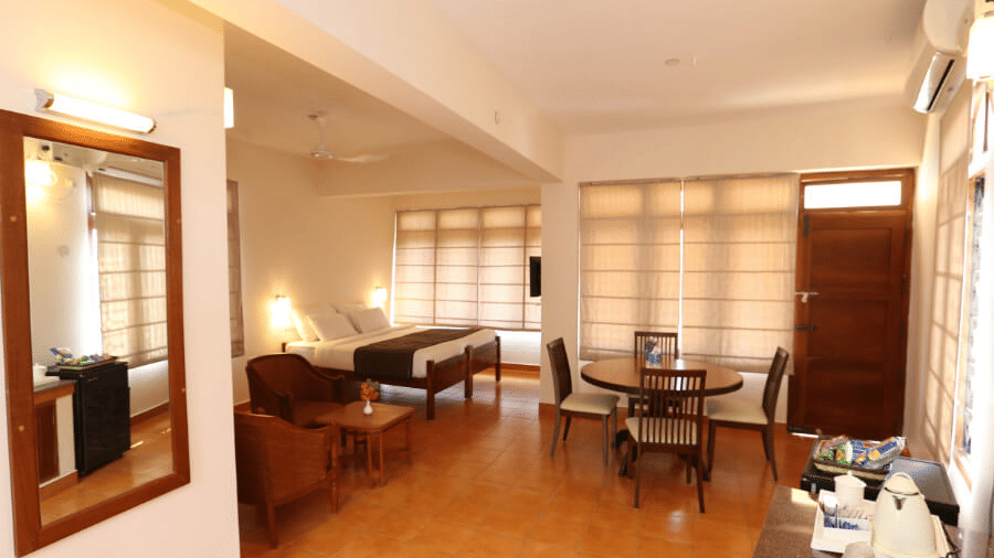 A superior room at Abad Serviced Villas, Kovalam with a bed, seating area, table, and large windows.