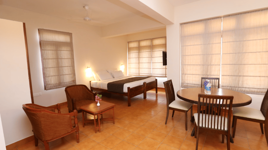 A seating area inside a superior room at Abad Serviced Villas, Kovalam with chairs, a sofa, and windows.