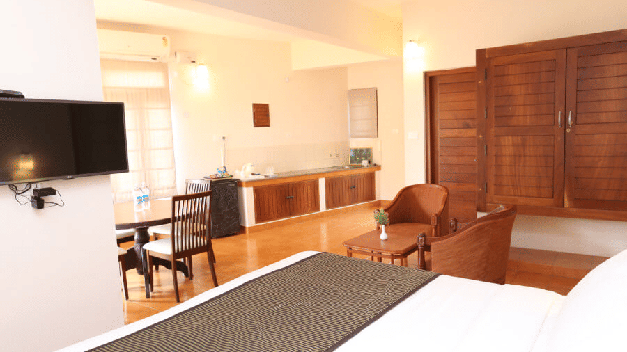 An interior space with a bed, seating area, table, and wall mounted television.