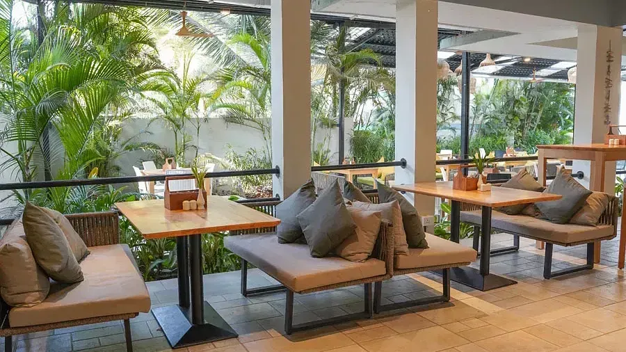 Dining area with comfortable sofas around tables in Aqua Vida Restaurant at Indie Stays Resort, Goa.