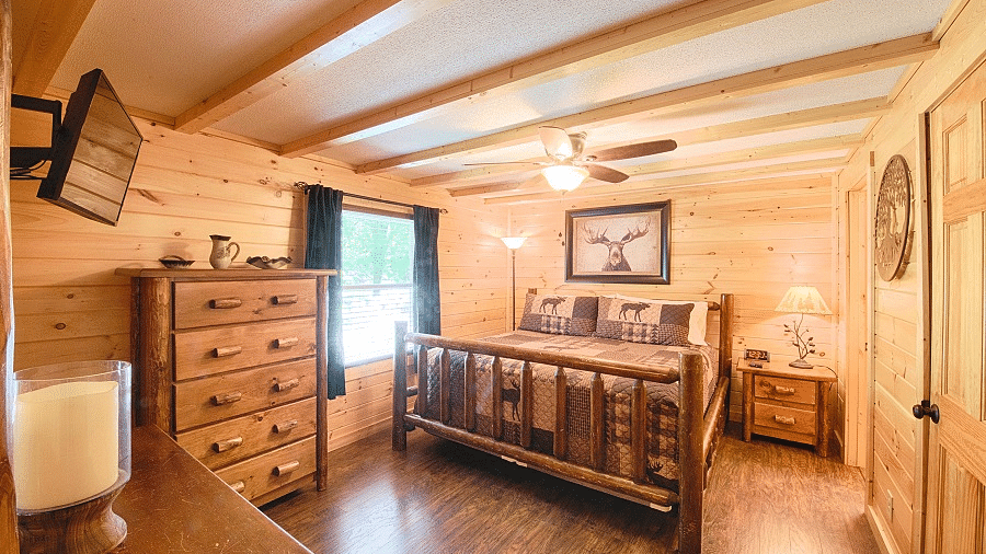 full view image of a bedroom featuring a cozy double bed with a beautiful picture wall mounted behind it - Historic Tapoco Lodge