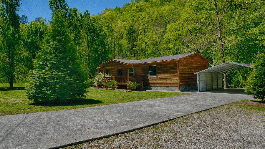 exterior shot of the river cabin taken from a distance featuring a huge evergreen conifer tree in front of it - Historic Tapoco Lodge