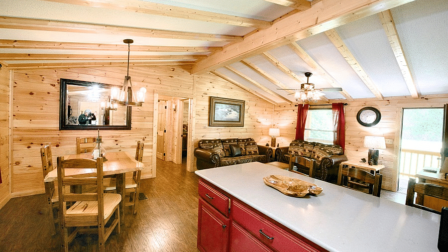 a white kitchen counter top with red colored shelves along with a dining area featuring a chandelier right above it - Historic Tapoco Lodge
