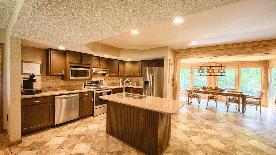 a well equipped kitchen with a service counter in the center along with the dining area in the far end - Historic Tapoco Lodge
