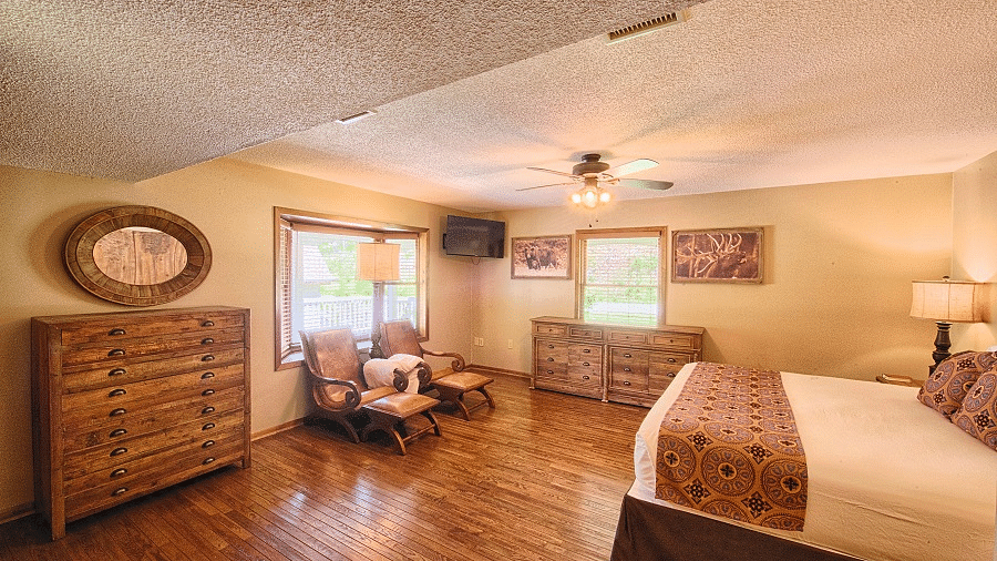 a room featuring a double bed and two reclining arm chairs along with a big wooden cupboard - Historic Tapoco Lodge
