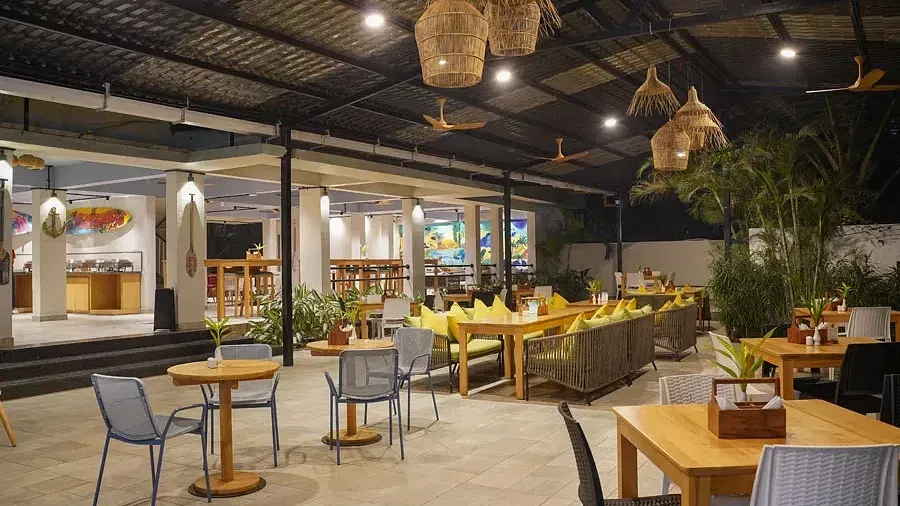 Dining area with comfortable chairs around tables in Aqua Vida Restaurant at Indie Stays Resort, Goa.
