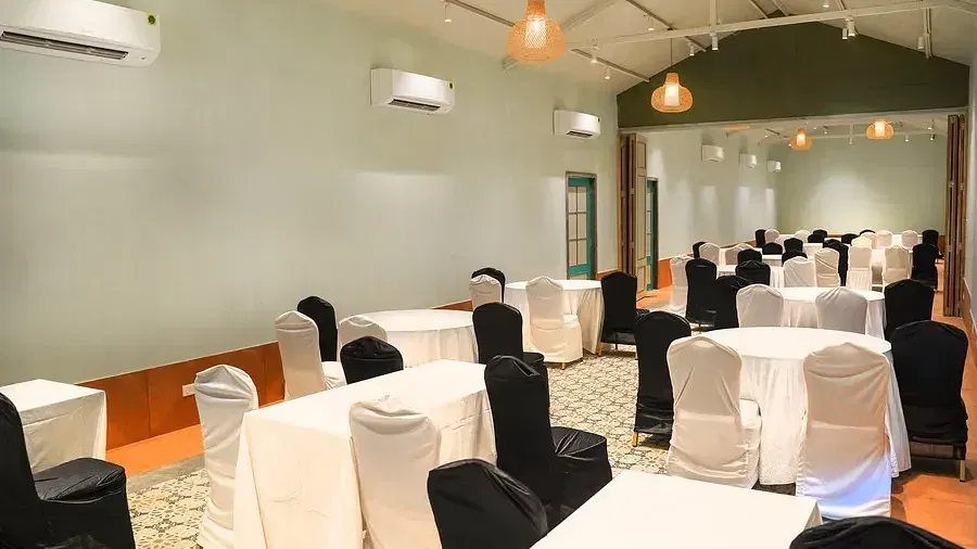 A conference hall set up with chairs around tables at Indie Stays Resort, Goa.