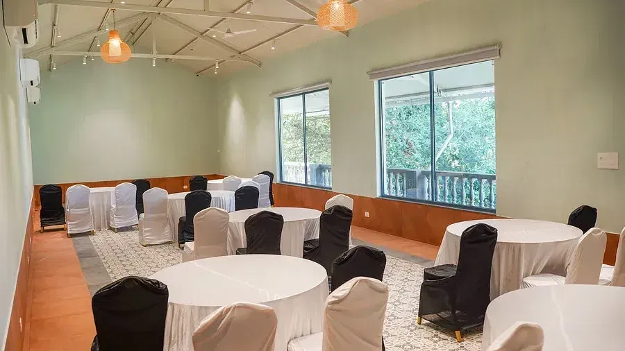 A conference hall set up with chairs around tables at Indie Stays Resort, Goa.